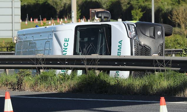 Four people rushed to hospital after ambulance flips on its side in crash with car and lorry